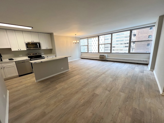 kitchen featuring stainless steel appliances, an inviting chandelier, light hardwood / wood-style floors, white cabinetry, and hanging light fixtures