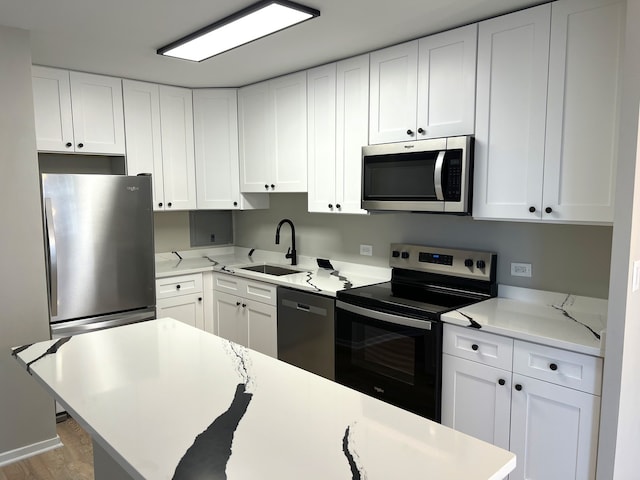 kitchen featuring light stone countertops, sink, light hardwood / wood-style floors, white cabinets, and appliances with stainless steel finishes