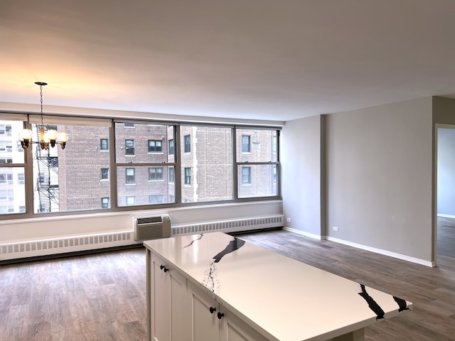 kitchen featuring hanging light fixtures, radiator heating unit, white cabinets, and a healthy amount of sunlight