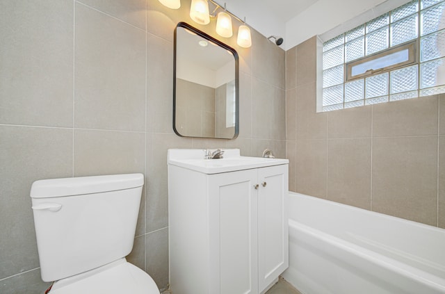 bathroom featuring a washtub, vanity, toilet, and tile walls