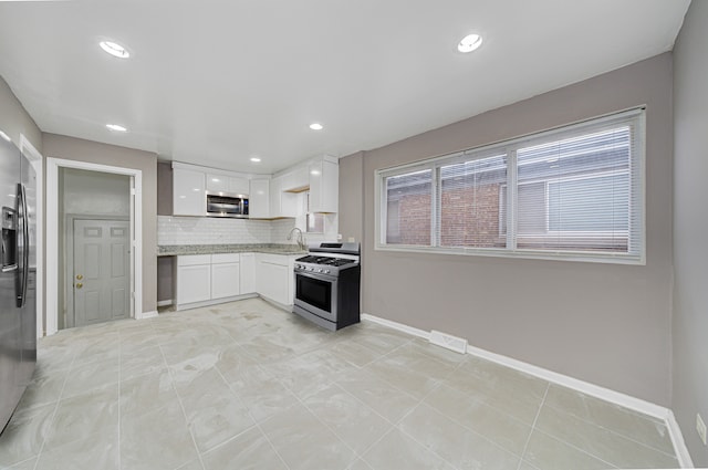 kitchen with backsplash, white cabinets, sink, light tile patterned flooring, and stainless steel appliances