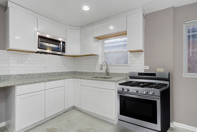 kitchen featuring decorative backsplash, sink, white cabinets, and stainless steel appliances