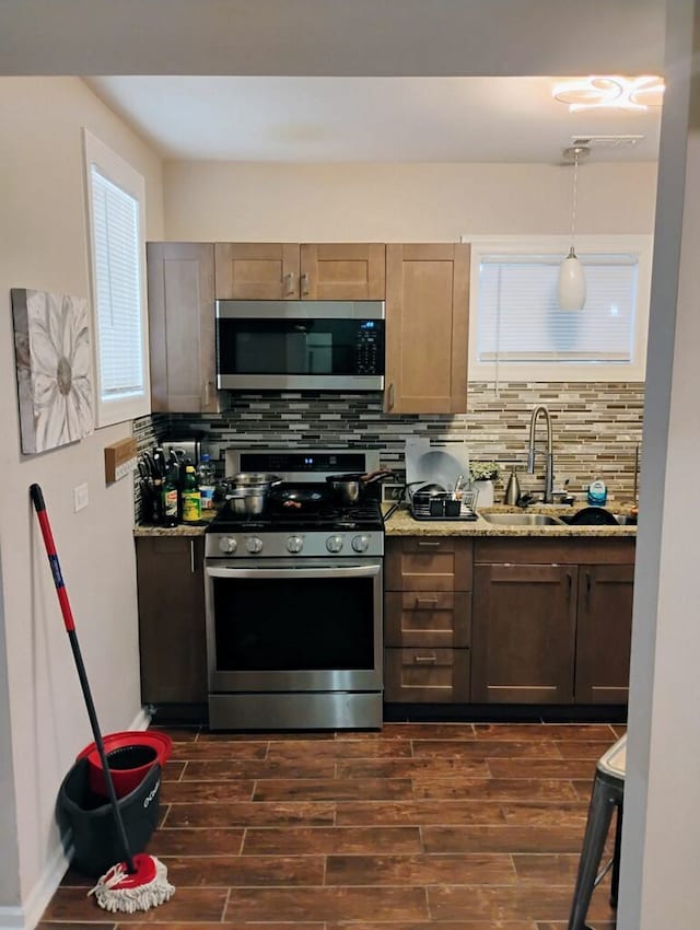 kitchen with dark hardwood / wood-style flooring, light stone countertops, appliances with stainless steel finishes, and tasteful backsplash