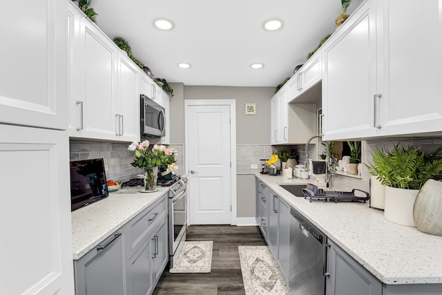 kitchen featuring backsplash, sink, dark hardwood / wood-style floors, appliances with stainless steel finishes, and light stone counters