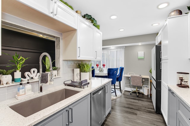 kitchen with dark hardwood / wood-style flooring, light stone counters, sink, dishwasher, and white cabinetry