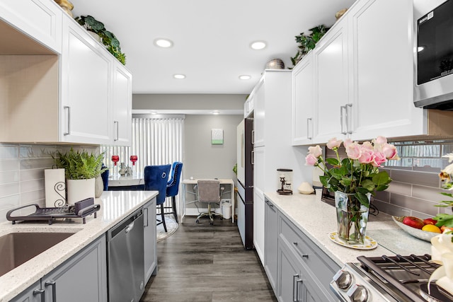 kitchen featuring light stone countertops, dark hardwood / wood-style flooring, stainless steel appliances, and white cabinets