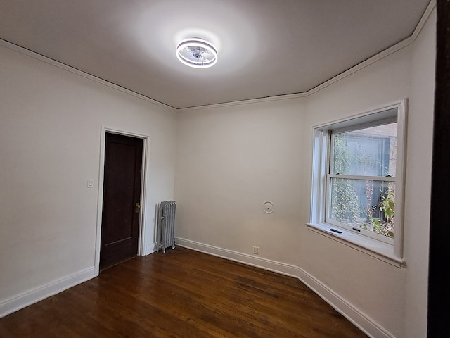 empty room with radiator heating unit, dark hardwood / wood-style flooring, and crown molding