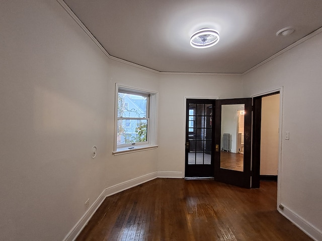 spare room with dark hardwood / wood-style flooring, ornamental molding, radiator heating unit, and french doors