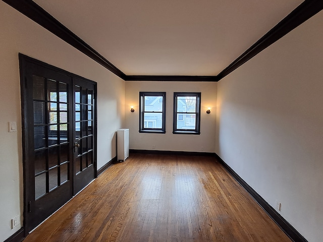 unfurnished room featuring radiator, crown molding, and wood-type flooring