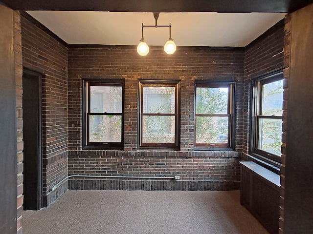 carpeted spare room featuring brick wall