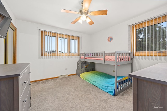 bedroom with multiple windows, ceiling fan, and light carpet