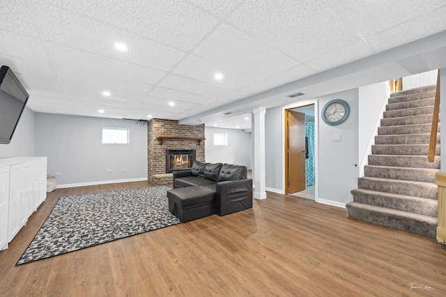 living room featuring hardwood / wood-style floors, a paneled ceiling, and a fireplace