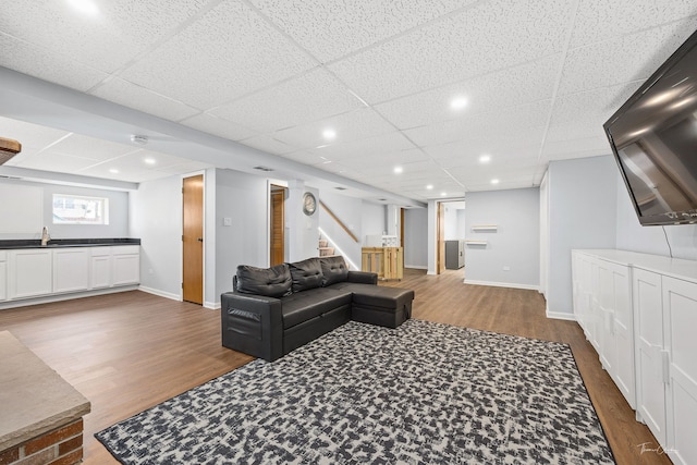 living room featuring sink, a drop ceiling, and hardwood / wood-style flooring