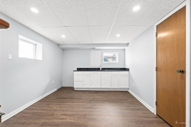 interior space featuring a wealth of natural light, white cabinetry, a drop ceiling, and dark wood-type flooring