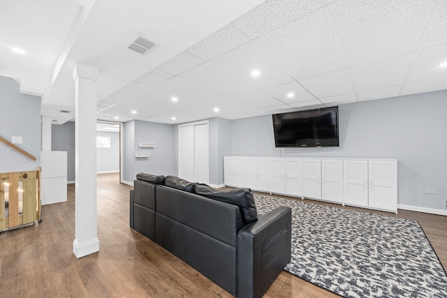 living room with dark hardwood / wood-style flooring and a drop ceiling