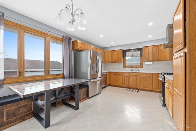 kitchen featuring sink, hanging light fixtures, ventilation hood, a chandelier, and appliances with stainless steel finishes