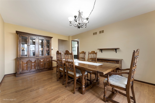 dining room with hardwood / wood-style floors and an inviting chandelier