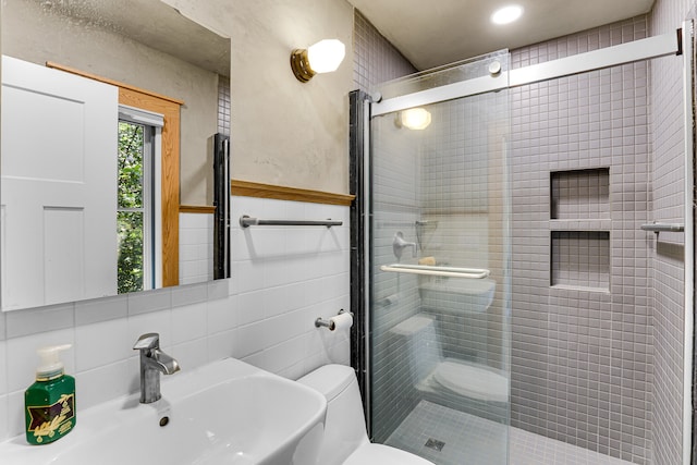 bathroom featuring toilet, a shower with door, sink, and tile walls