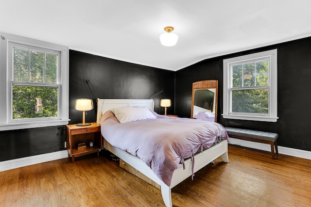 bedroom featuring hardwood / wood-style floors, lofted ceiling, and multiple windows