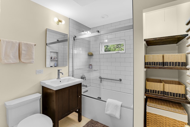 full bathroom with tile patterned floors, vanity, toilet, and bath / shower combo with glass door