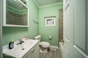 bathroom featuring crown molding, hardwood / wood-style floors, vanity, and toilet