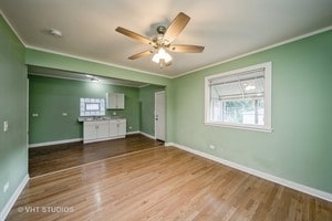 interior space featuring ceiling fan, wood-type flooring, and ornamental molding