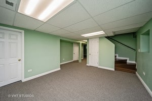 basement featuring carpet flooring and a paneled ceiling