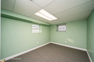 basement with a paneled ceiling and dark carpet