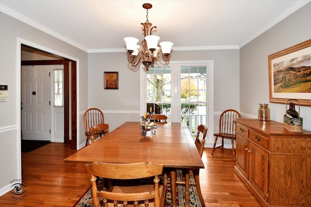 dining area with crown molding, hardwood / wood-style floors, and a notable chandelier