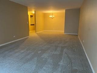 carpeted empty room featuring a notable chandelier