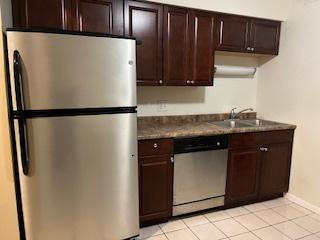 kitchen with dark brown cabinetry, sink, light tile patterned flooring, and stainless steel appliances