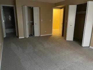 unfurnished bedroom with dark carpet and two closets