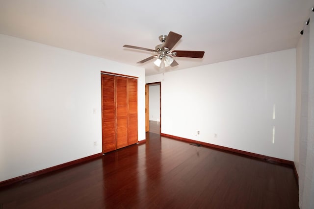 unfurnished bedroom featuring ceiling fan, dark hardwood / wood-style flooring, and a closet