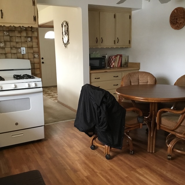 kitchen with cream cabinetry, white gas range, and light hardwood / wood-style flooring