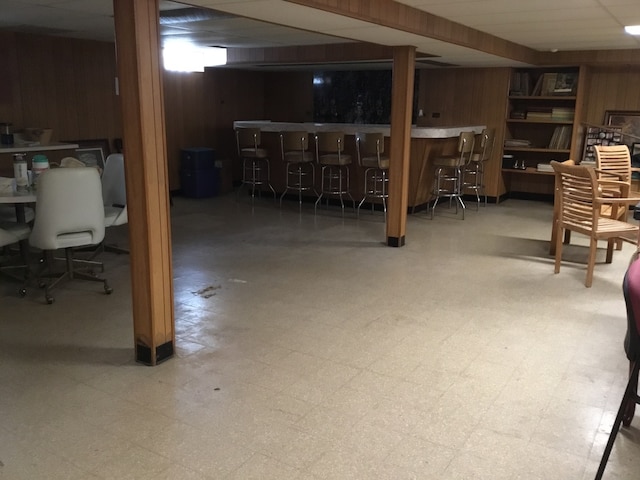 basement featuring bar area and wood walls