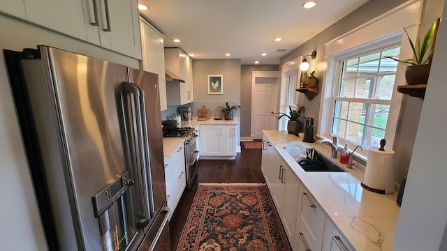 kitchen with dark hardwood / wood-style flooring, light stone counters, stainless steel appliances, sink, and white cabinetry