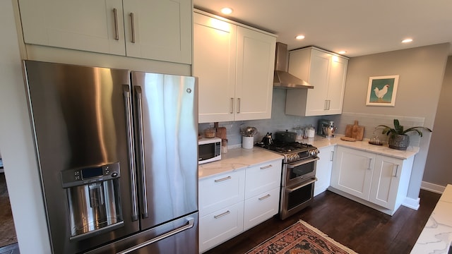 kitchen with white cabinetry, light stone countertops, wall chimney exhaust hood, and appliances with stainless steel finishes