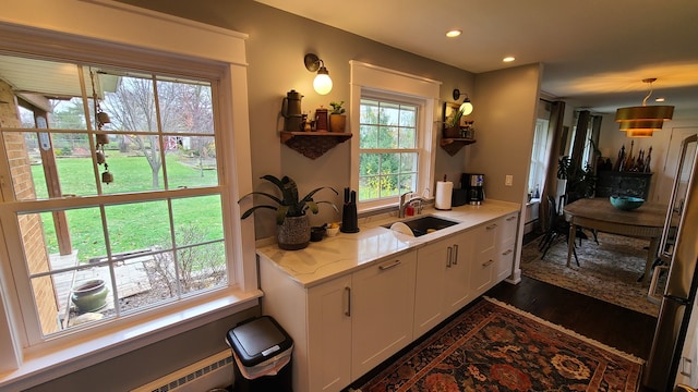 kitchen featuring light stone countertops, white cabinetry, sink, dark wood-type flooring, and decorative light fixtures