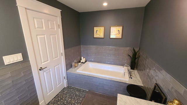 bathroom featuring tile patterned floors, a relaxing tiled tub, and tile walls