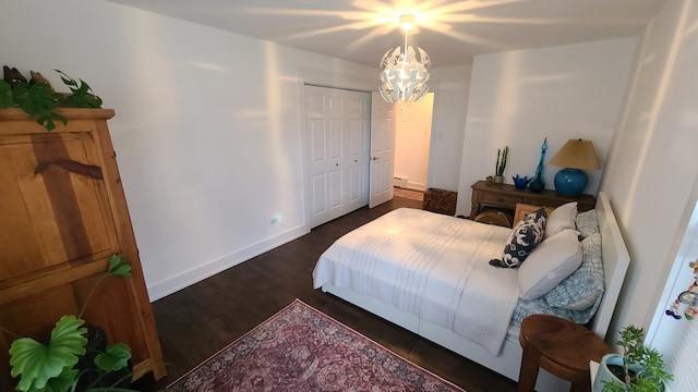 bedroom with a closet, dark hardwood / wood-style floors, and an inviting chandelier