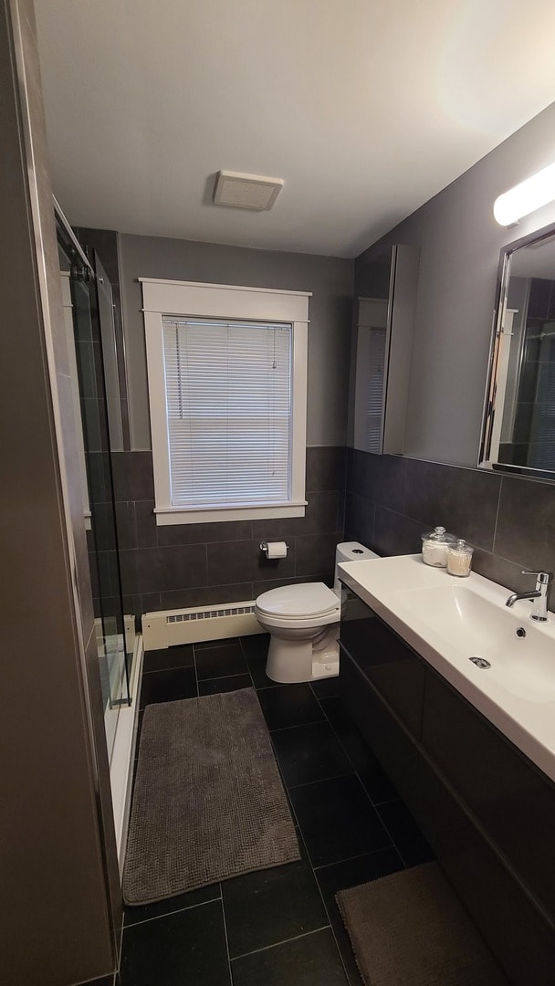 bathroom with tile patterned floors, a baseboard heating unit, tile walls, and walk in shower