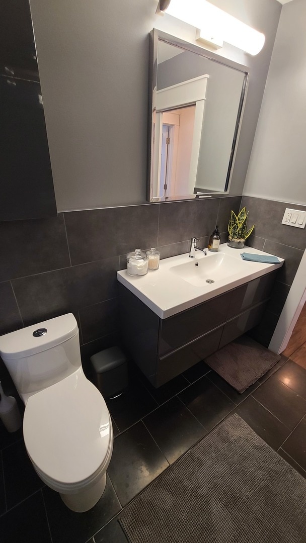 bathroom with tile patterned floors, toilet, tile walls, and sink