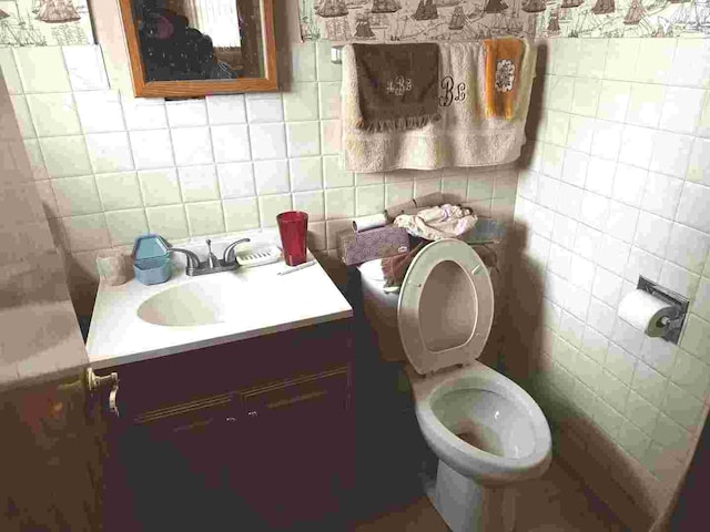 bathroom featuring vanity, toilet, and tile walls