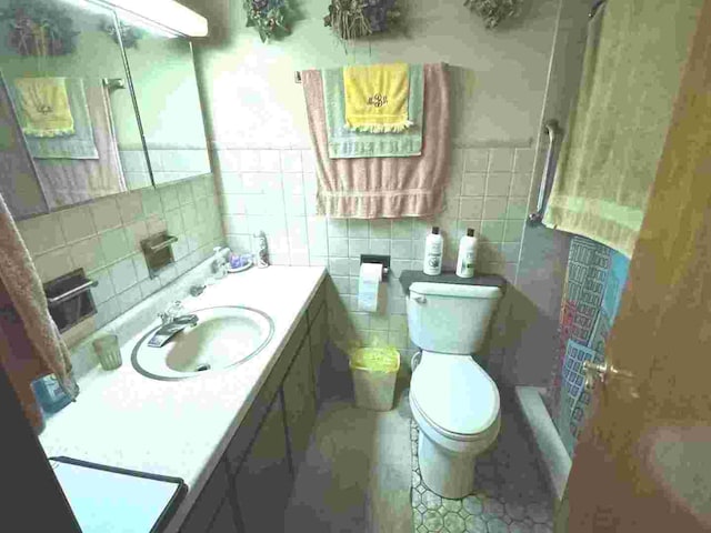 bathroom featuring walk in shower, vanity, toilet, and tile walls