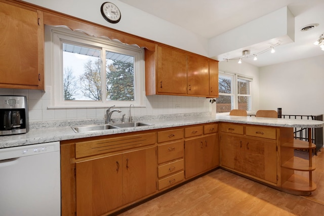 kitchen with white dishwasher, decorative backsplash, sink, and light hardwood / wood-style flooring