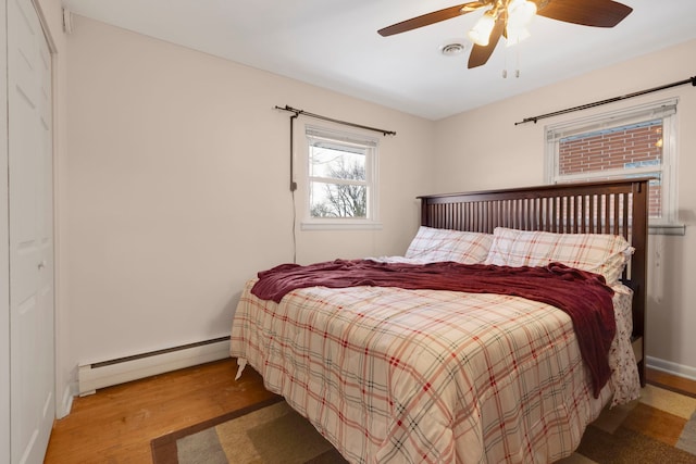 bedroom featuring hardwood / wood-style floors, ceiling fan, and baseboard heating