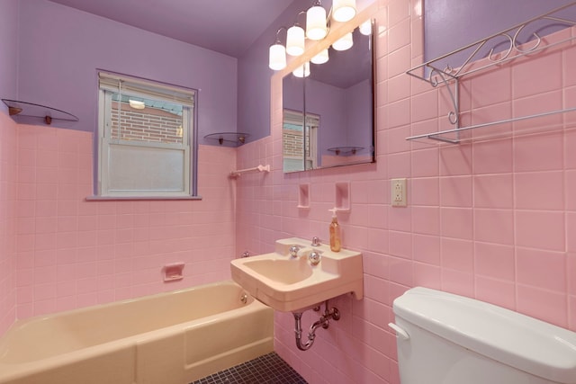 bathroom with tile patterned floors, tiled shower / bath combo, toilet, and tile walls