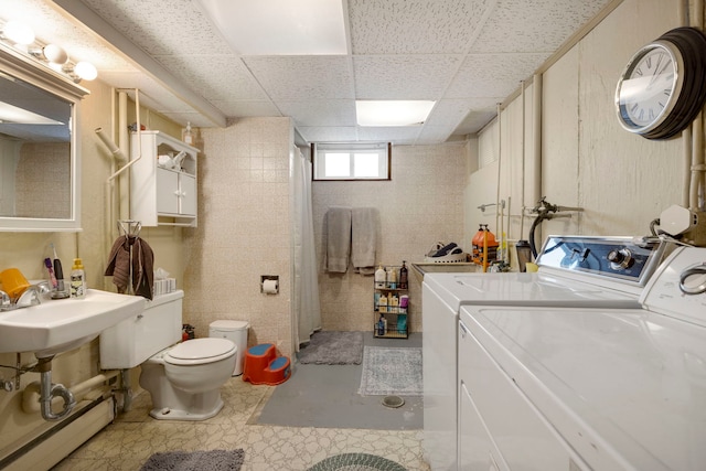 clothes washing area with baseboard heating, sink, and independent washer and dryer