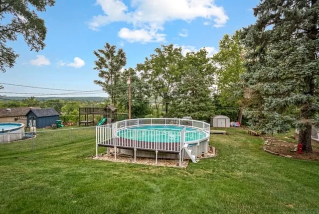 view of swimming pool featuring a yard, a playground, and a storage unit