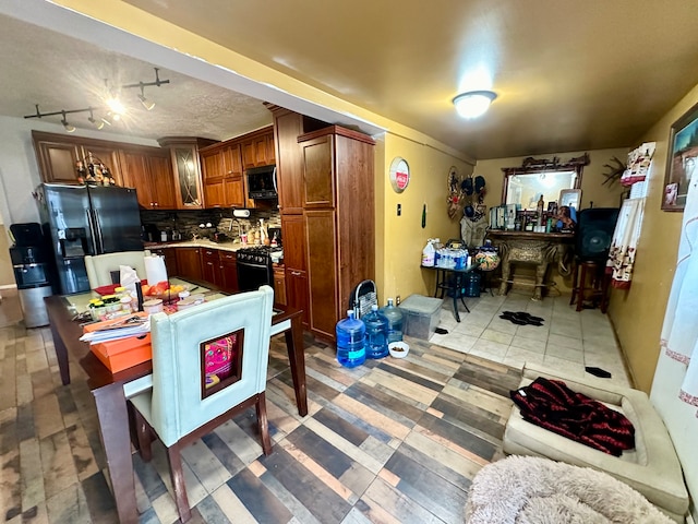 kitchen with decorative backsplash, rail lighting, and black appliances